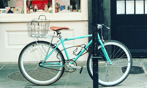 Light blue bicycle rests on a street light on the sidewalk of a small town in Clarkesville GA. Storefront with trinkets for sale visible in background.